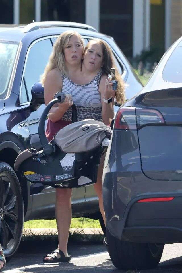 连体双胞胎艾比 (Abby) 和布列塔尼·亨塞尔 (Brittany Hensel) 坐在婴儿汽车座椅上。