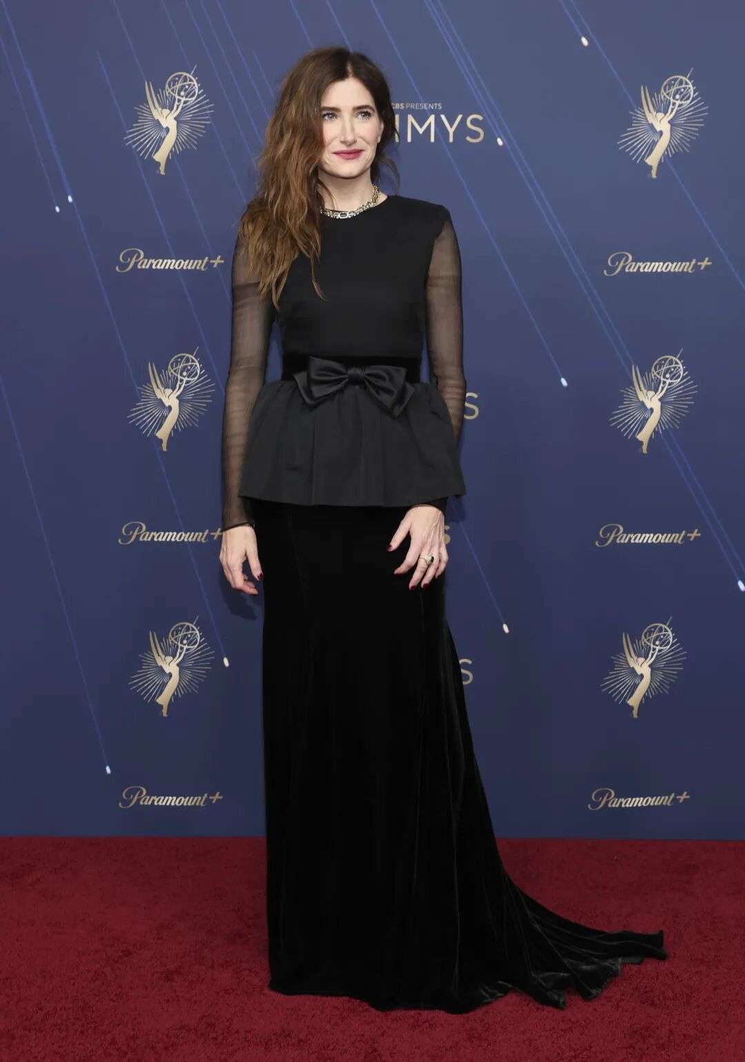 Kathryn Hahn wearing long black dress with a bow around the waits and sheer black sleeves