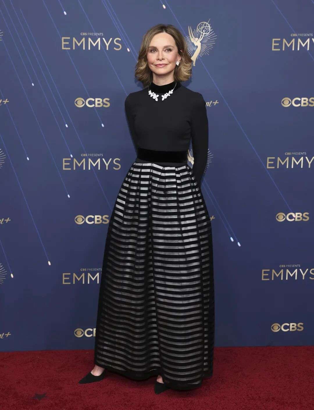 Calista Flockhart wearing a long black top with a black and silver striped skirt