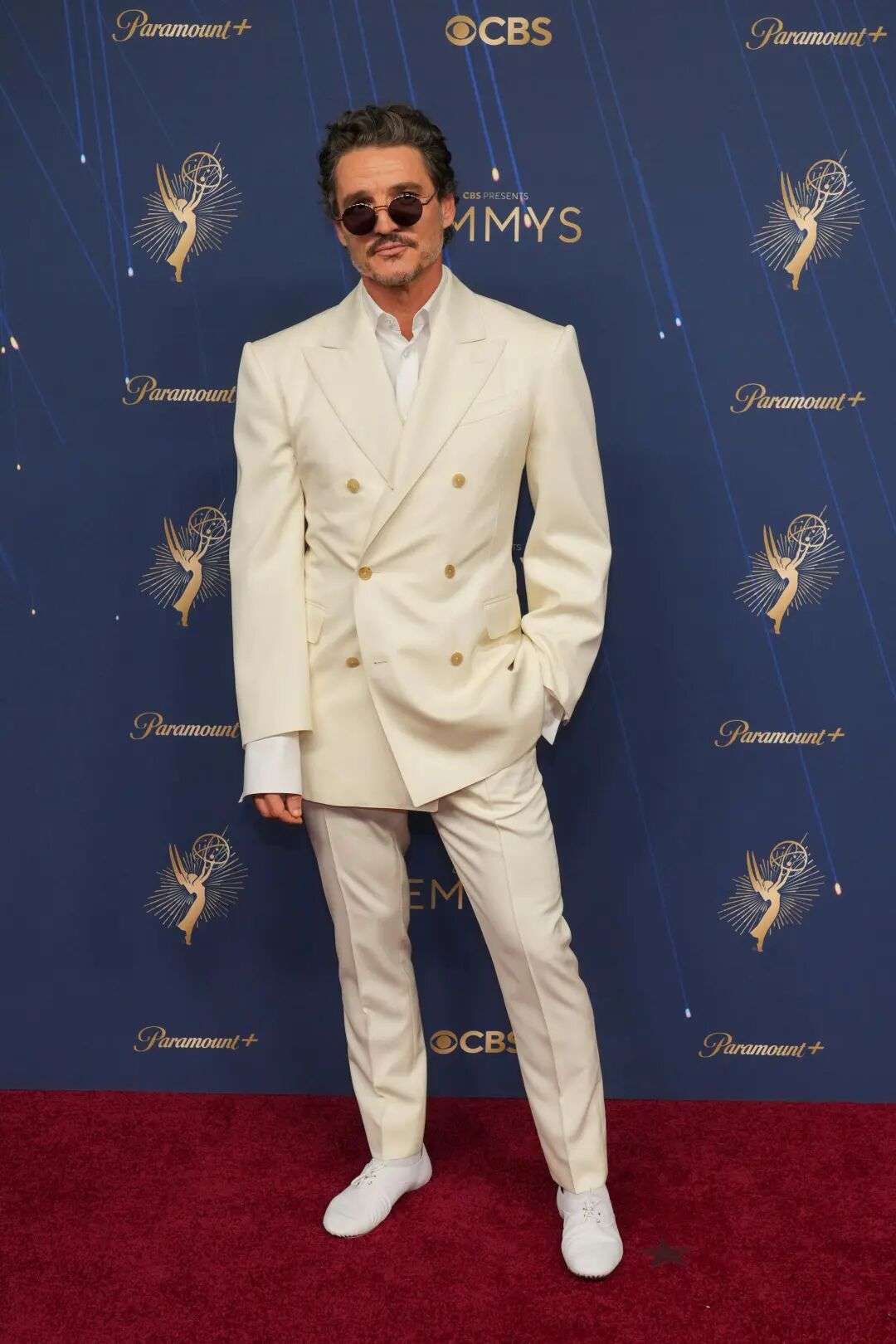 Pedro Pascal wearing a double breasted white suit and sunglasses