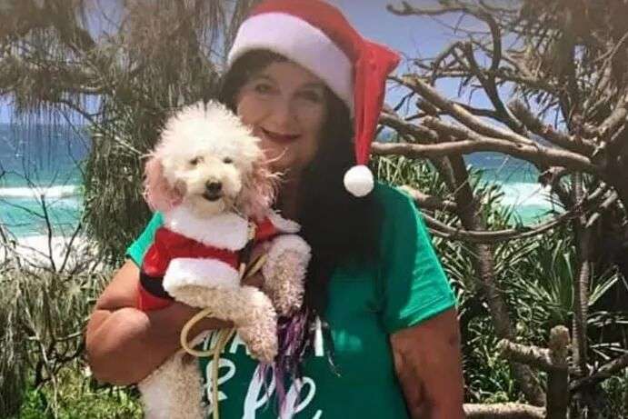 A woman dressed as a Christmas elf holding a small dog.