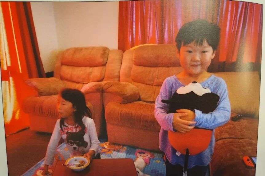 Yuna sits down on the floor while Minu holds a mickey mouse toy.