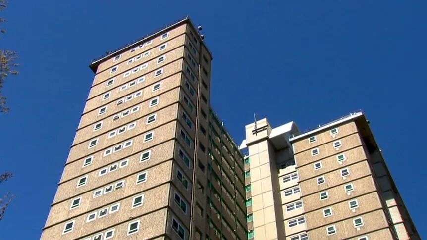 A low angle pic of public housing towers in front of a blue sky