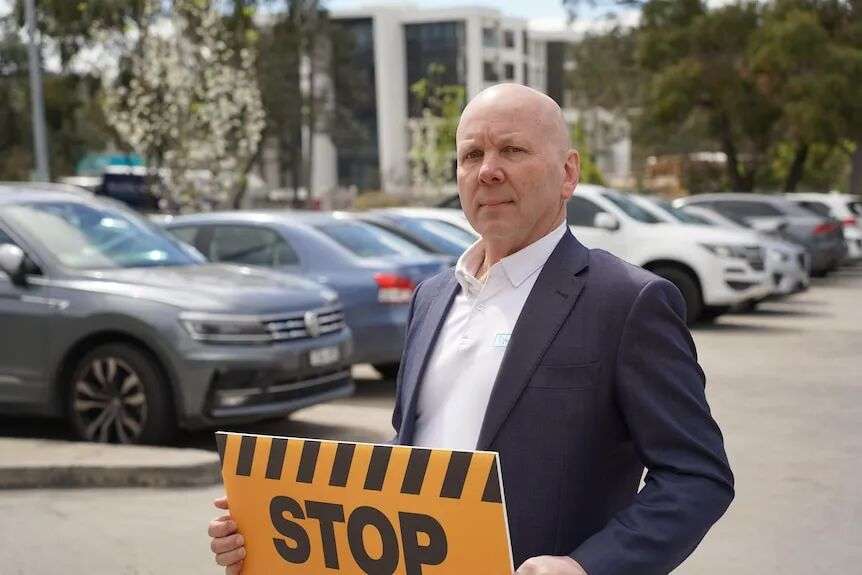 Wayne holds an anti-development placard in a carpark in Greensborough