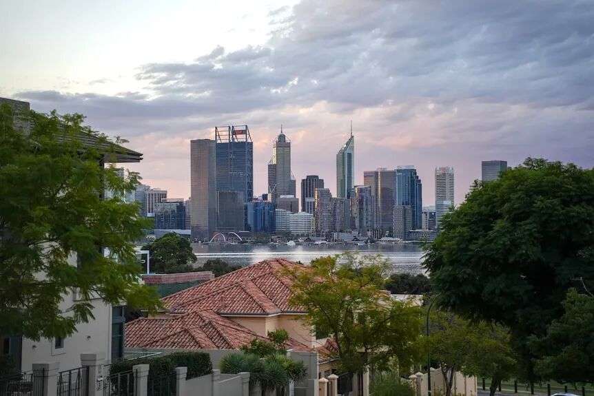 Residential rooftop and street trees in the foreground with the Swan River and Perth CBD skyline at the back