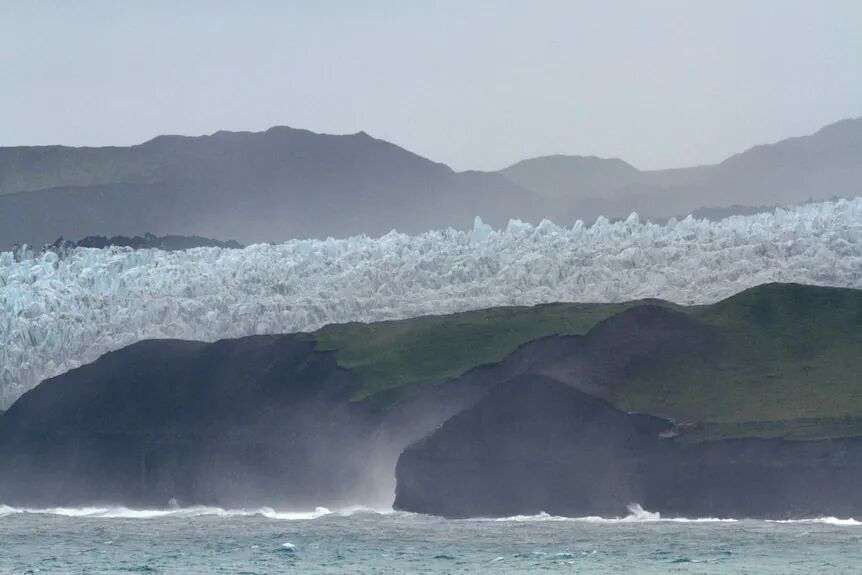 Glacier on Heard Island, water in the foreground. Picture is hazy.