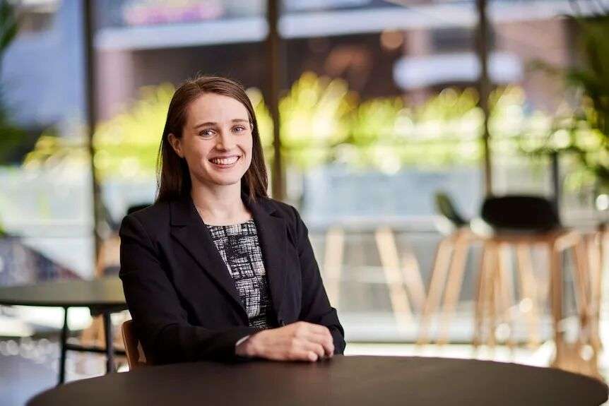 A woman sits at a table smiling.