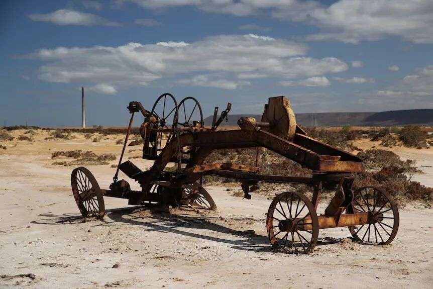 Looking across the saltpan to the old power plant with a rusted carriage in the foreground.