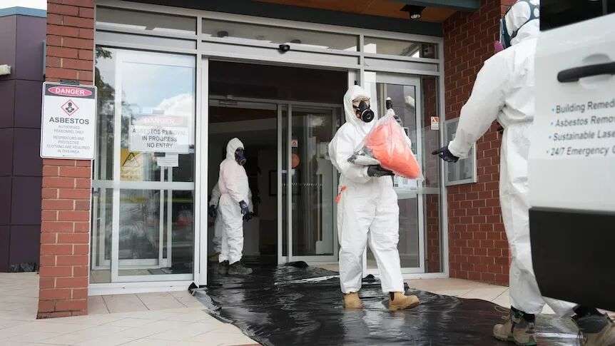 People dressed in white, all-body suits at the entrance to a building.