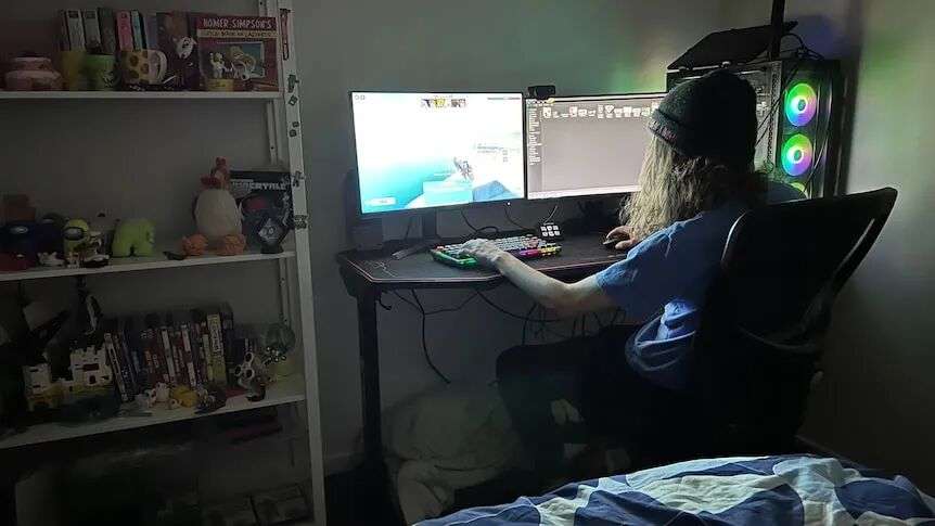 A child plays Roblox on a computer in their bedroom.