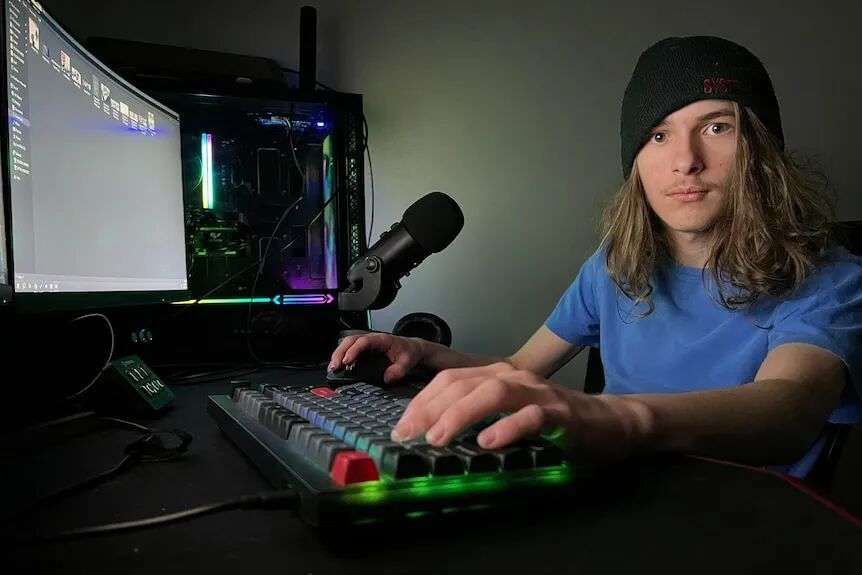 A teenager sits at his gaming desk