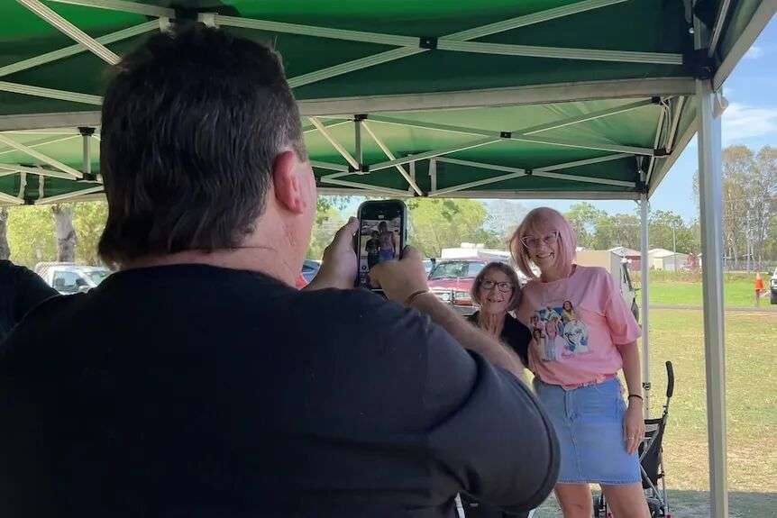 A man takes a photo of two women dressed like each other.