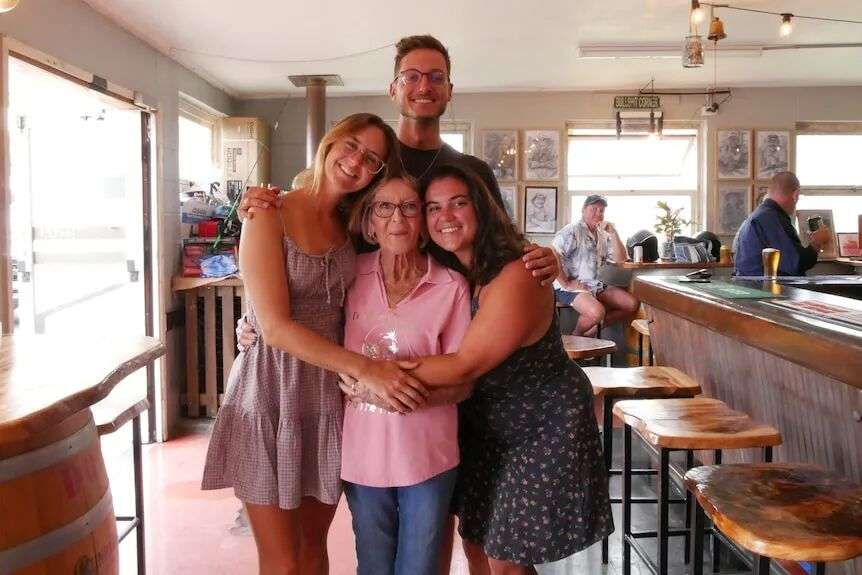 Three people hugging a short grandmother.