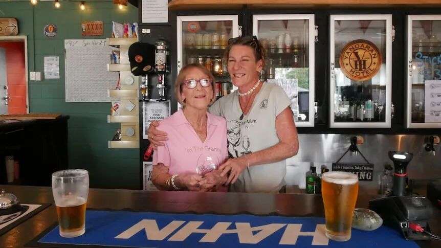 Two women hugging behind a bar.