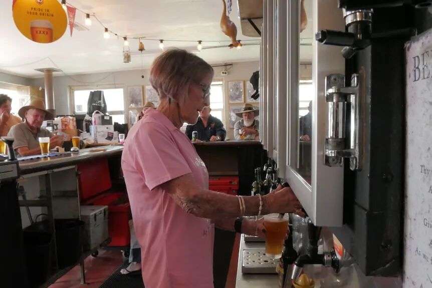 A woman bought a beer behind a busy bar.