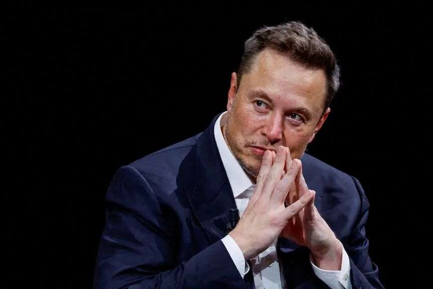 Elon Musk holding his hands up to his mouth.