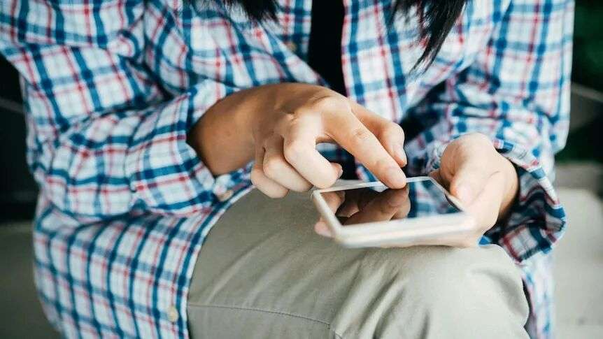 close up of woman in blue check shirt looking at mobile phone