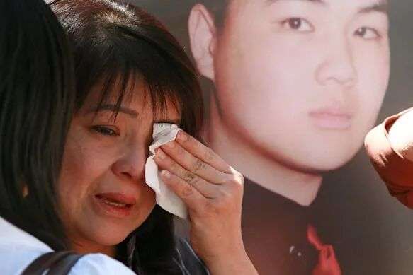 Kim Nguyen weeps in front of a poster of her son, Van Nguyen, in 2006, one year after he was executed.