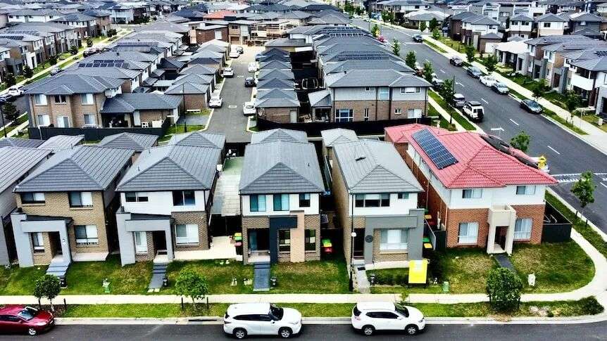 Aerial shot of dozens of houses in neat rows in a new outer-suburban housing estate.