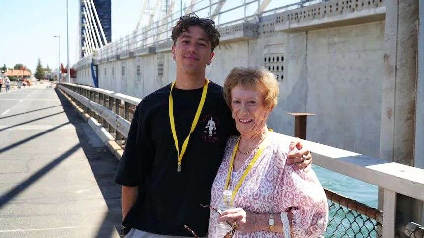 A young man and elderly woman pose for a photo together