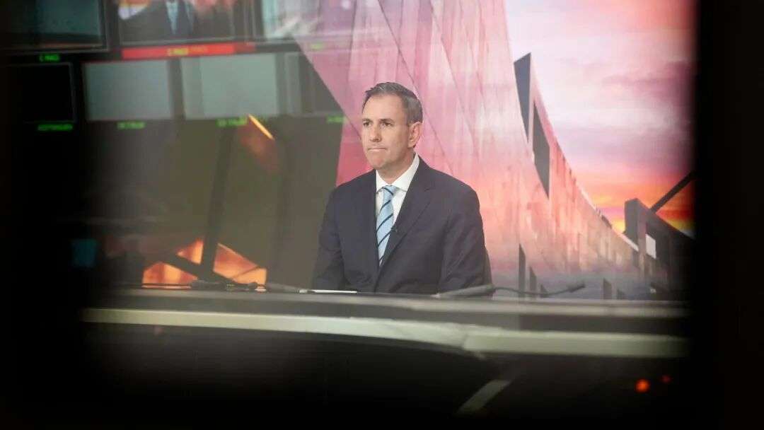 Jim Chalmers sits at a studio desk in front of a TV camera.