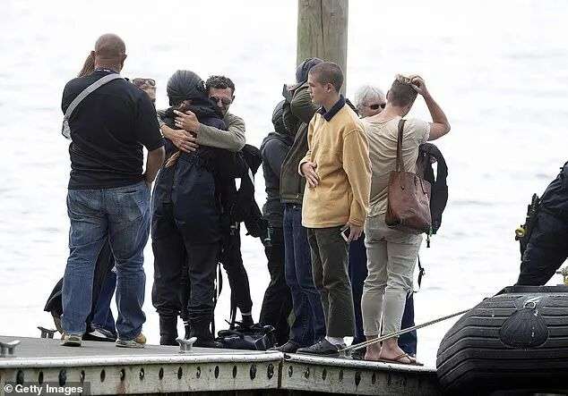Families of victims killed in the White Island eruption are pictured upon their return from observing a minute's silence near the site, a week after the disaster