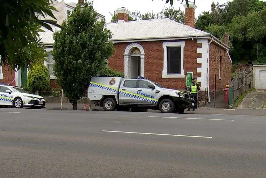 Police car and officers outside a brick house.