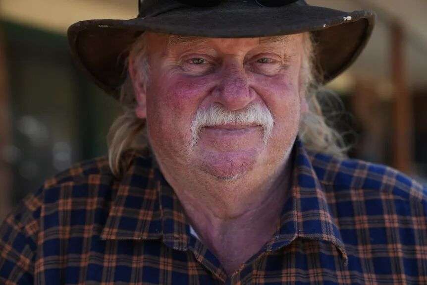 An older man with white hair and a moustache with a broad brim hat.